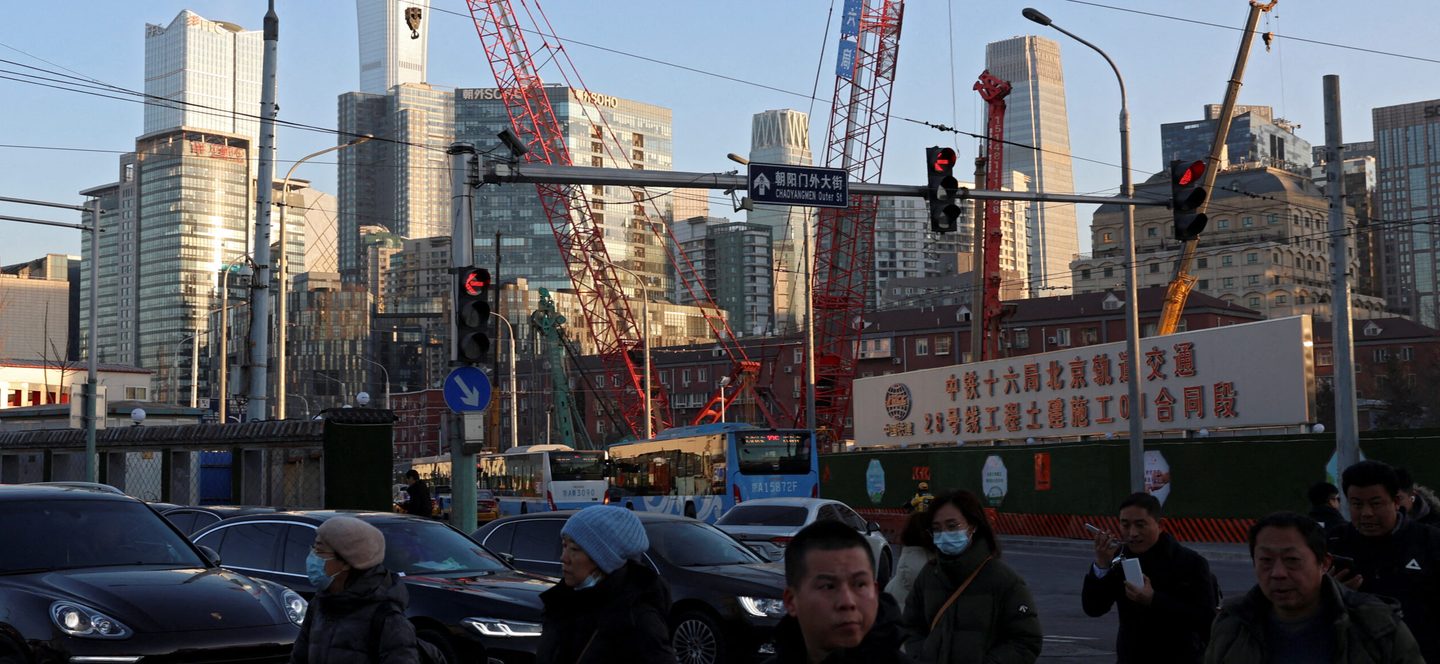 Pedestrians cross an intersection near a construction site in Beijing. China is focusing on exports of EVs, batteries and solar cells