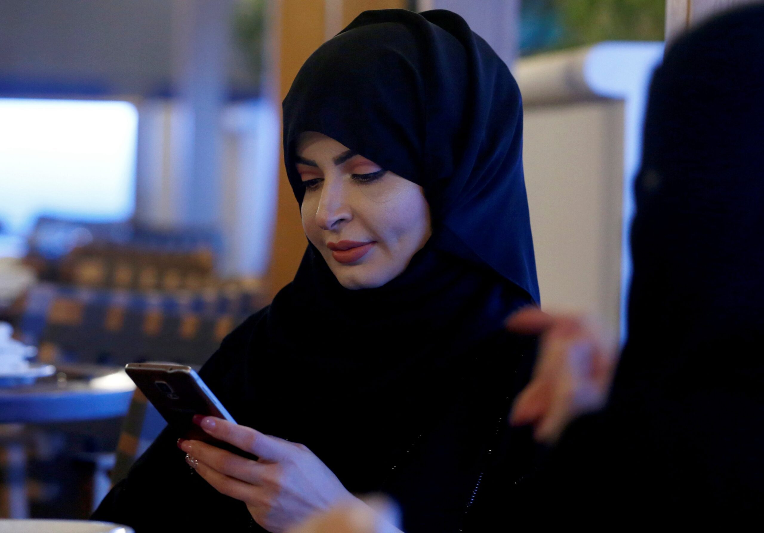 A woman uses her mobile phone in a Riyadh cafe. According to data, Saudi Arabians spend five hours a day on their smartphones