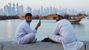 People rest on a wall at the Doha Corniche with the Doha skyline seen in the background in Doha, Qatar, February 13, 2024. REUTERS/Clodagh Kilcoyne