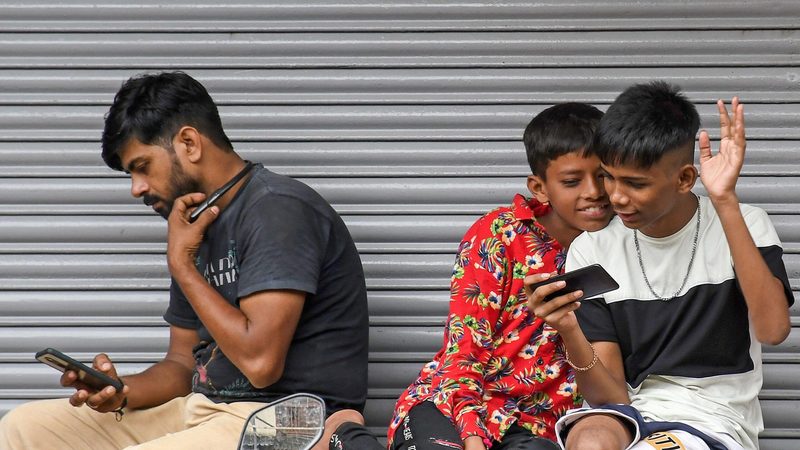 People engrossed in their smartphones in Mumbai. Vodafone Idea has lost around 210m subscribers since 2018