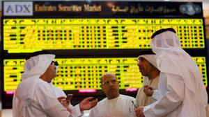 Investors confer at Abu Dhabi Securities Exchange. The market's all-time high came in November 2022