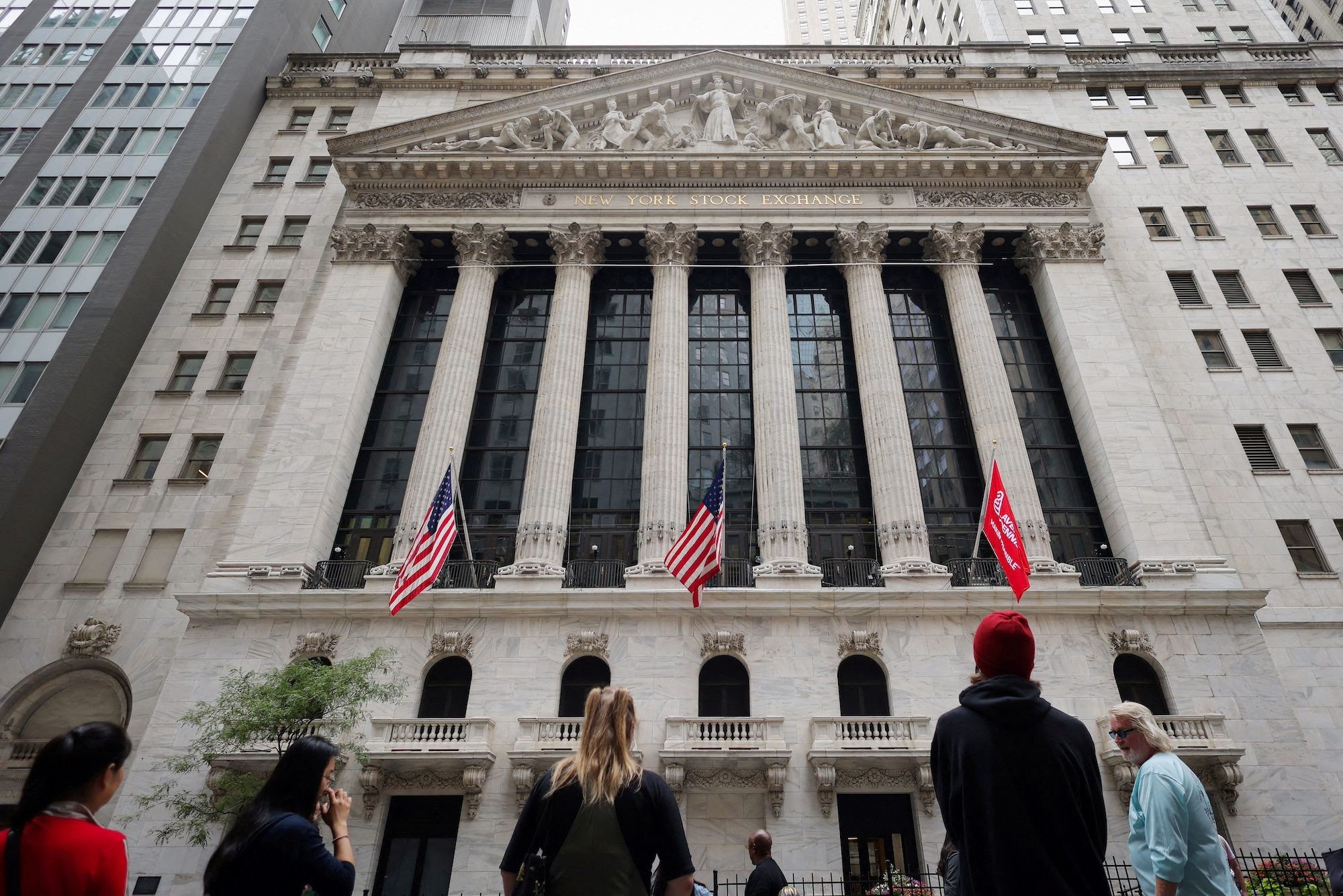 FILE PHOTO: People look toward the New York Stock Exchange (NYSE) before the Federal Reserve announcement in New York City, U.S., September 18, 2024. REUTERS/Andrew Kelly/File PhotoPeople await the announcement of the Fed decision on interest rates outside the New York Stock Exchange; Gulf banks followed suit, lowering rates