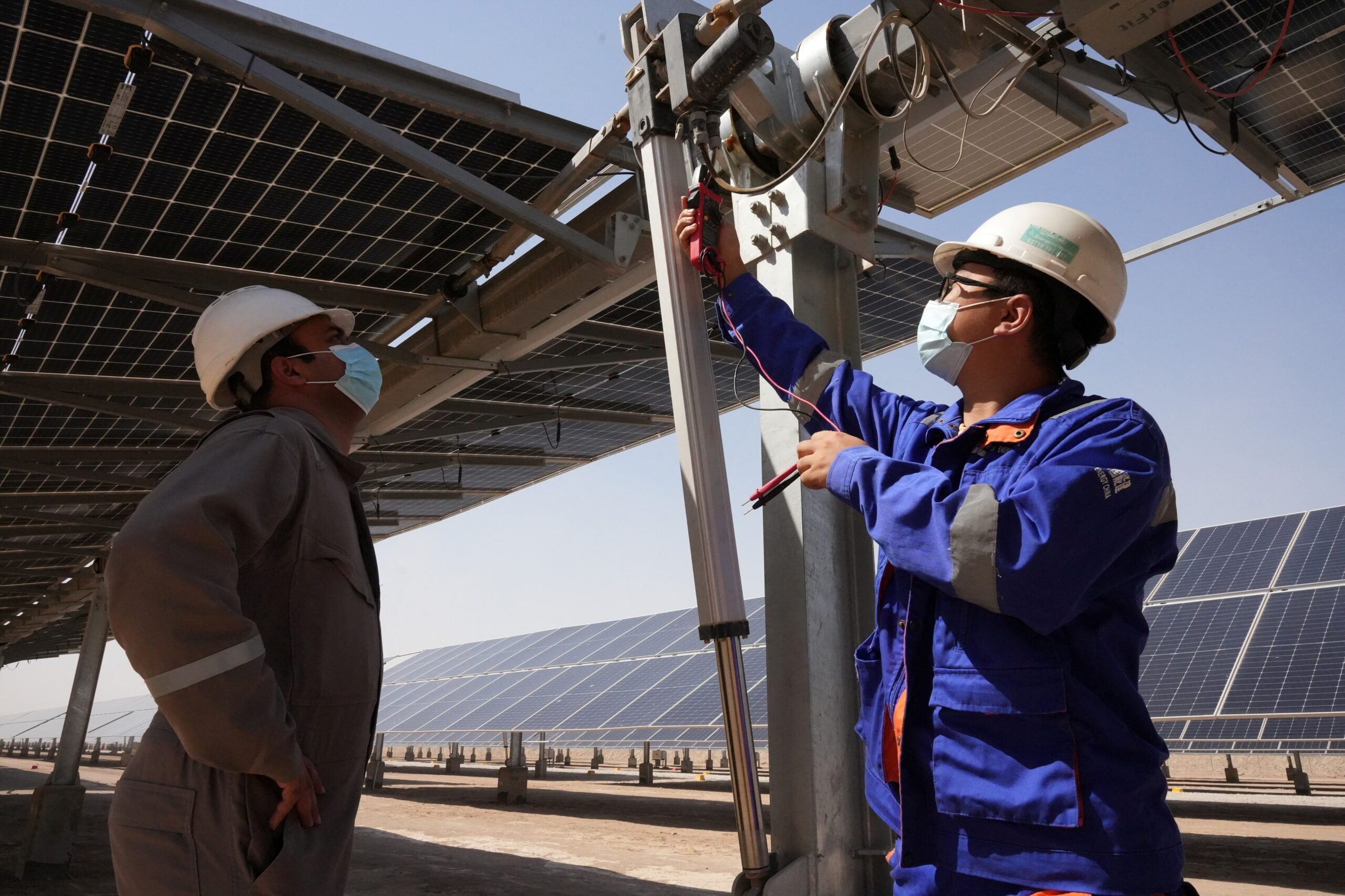 Workers check solar panels in Basra, Iraq. Renewable energy projects are growing across the Middle East
