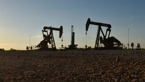 Pump jacks operate in front of a drilling rig in an oil field in Midland, Texas