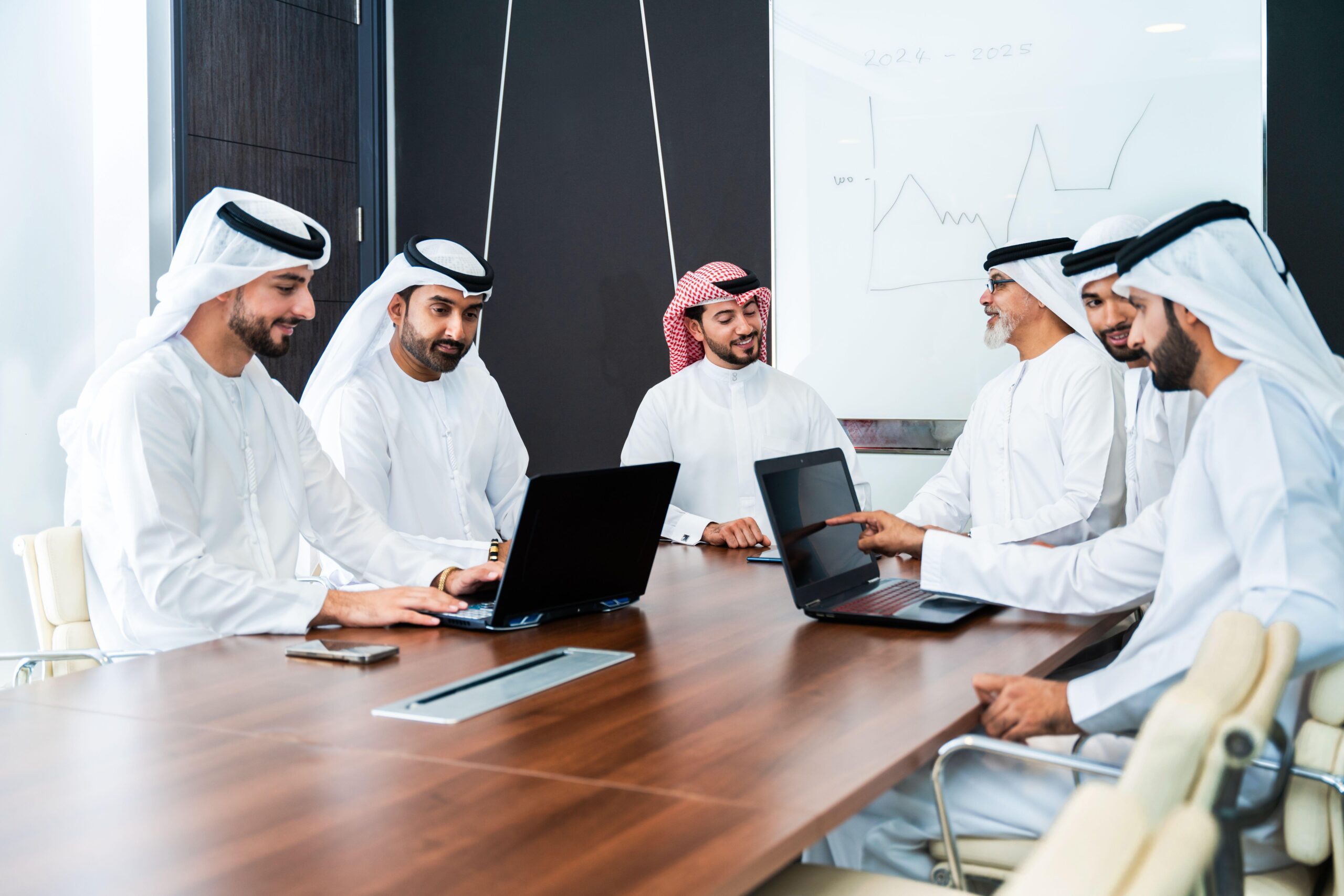 Group of corporate arab businessmen meeting in the office - Middle-eastern businesspeople wearing emirati kandora working in a meeting room, Dubai