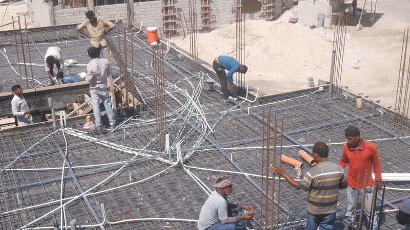 construction over-runs delays Asian construction workers working on a building, Kingdom of Bahrain