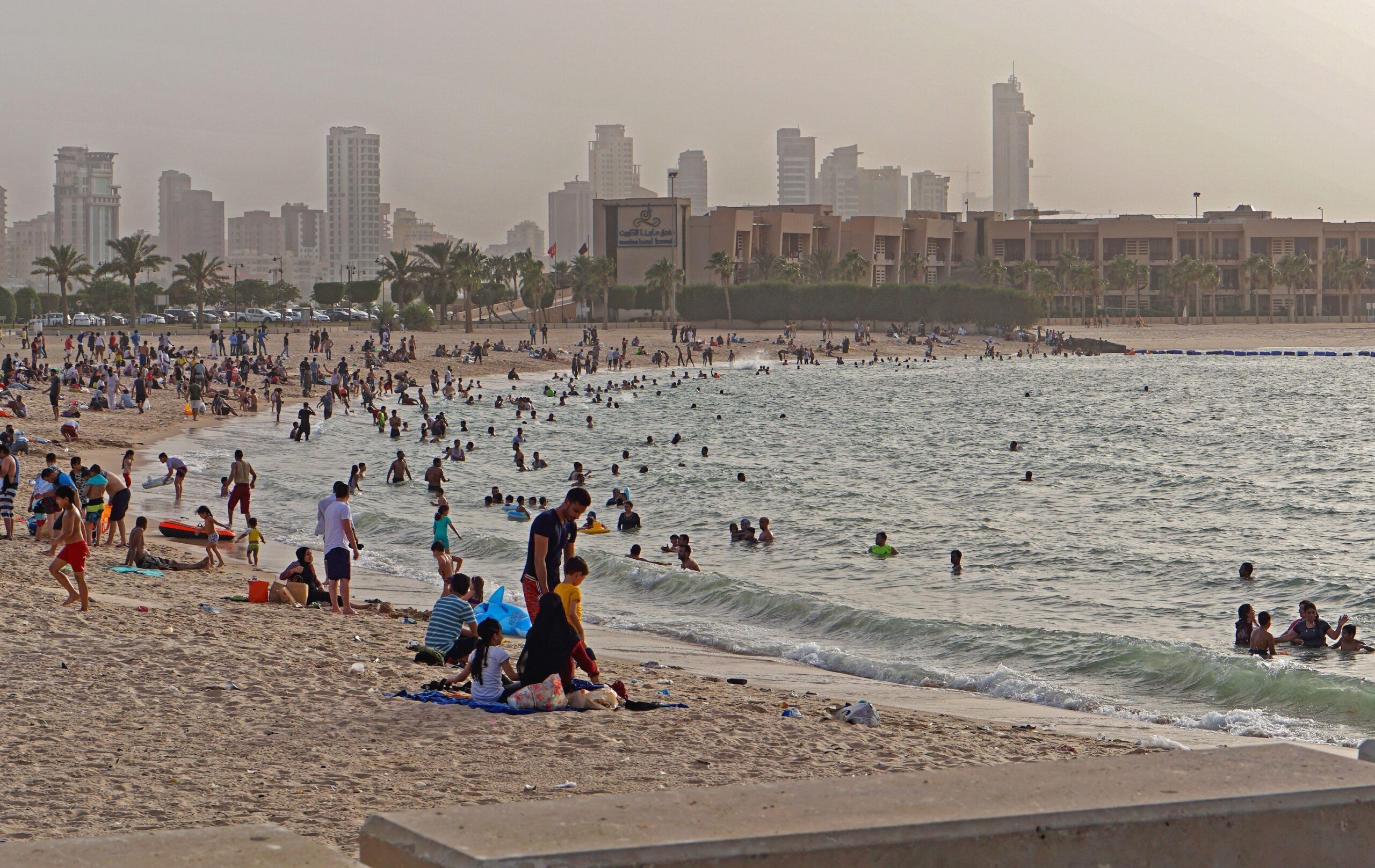 People on Kuwait City's Marina Beach. It is estimated that housing costs in Kuwait absorb one third of an average household's income