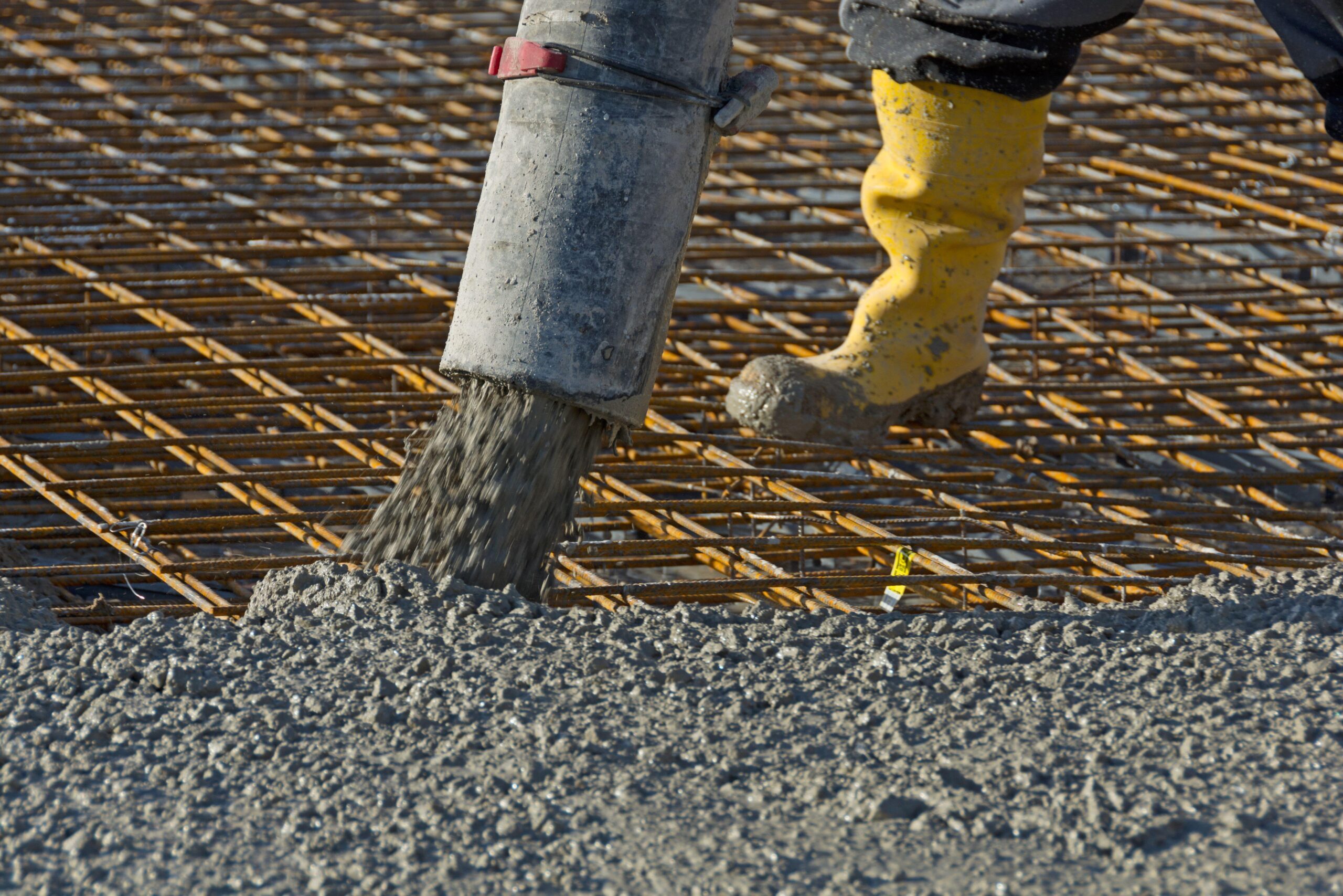 Construction worker pours concrete on rebar using concrete pump