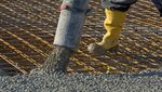 Construction worker pours concrete on rebar using concrete pump