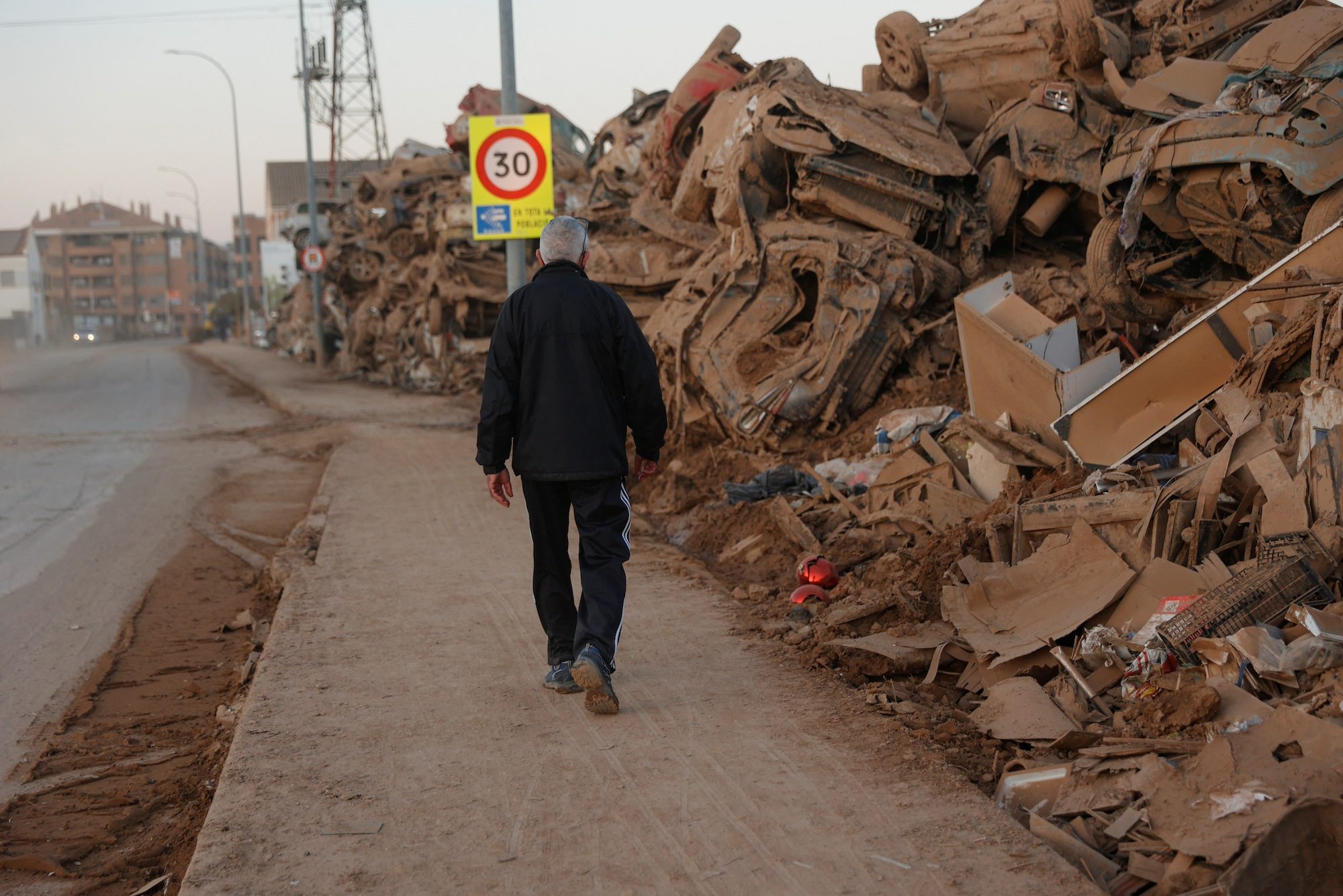 A month after floods struck at the end of October, a man walks past damaged cars in Valencia, Spain