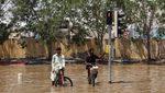 People sitting on bicycles look on amidst flood water following heavy rainfall, in Dubai, United Arab Emirates, April 19, 2024