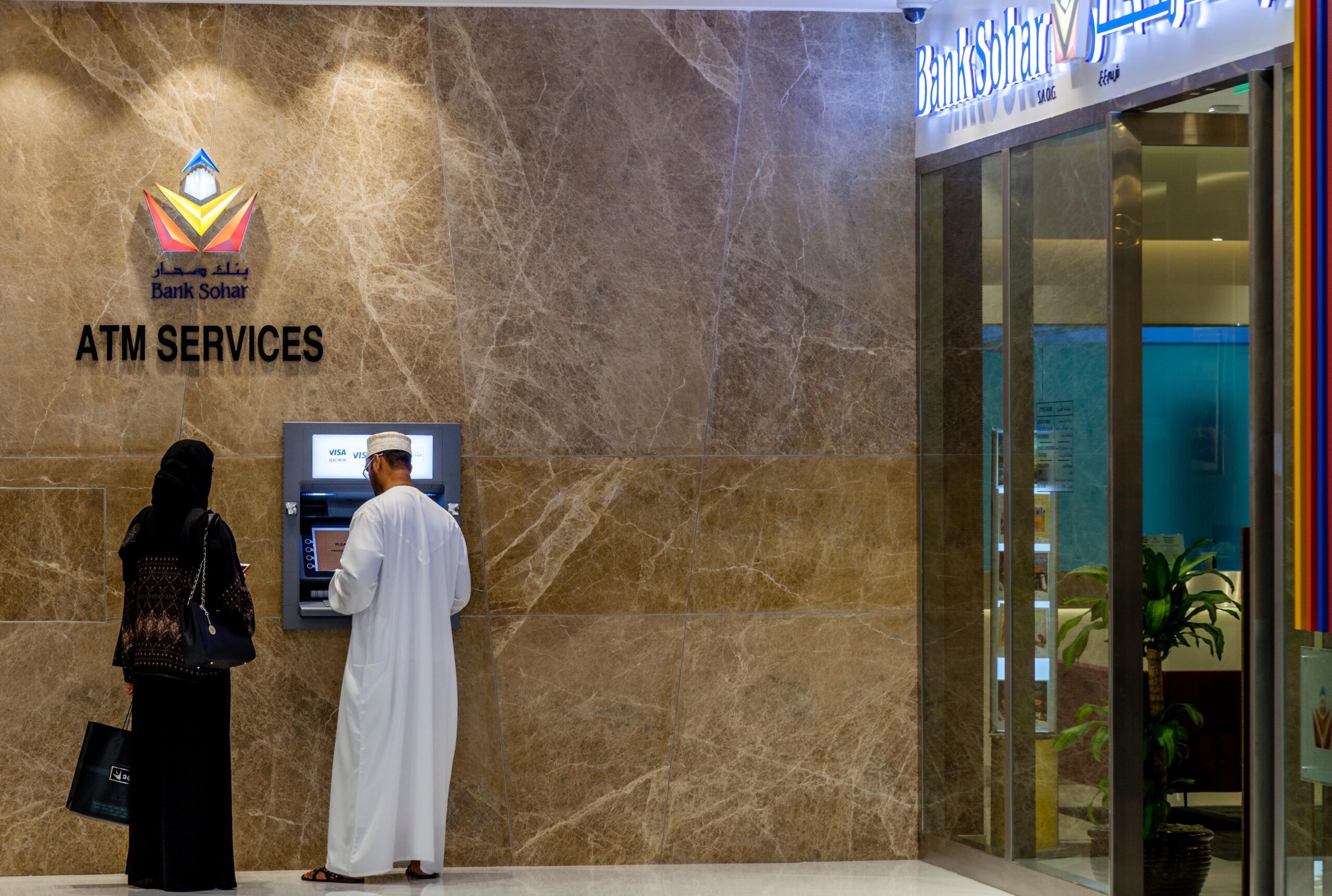 Customers use an ATM outside a Bank Sohar branch in Muscat