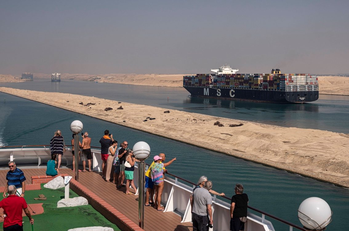 Passengers on a cruise ship watch container vessels in the Suez Canal. Egypt's GDP is projected to grow at 5%
