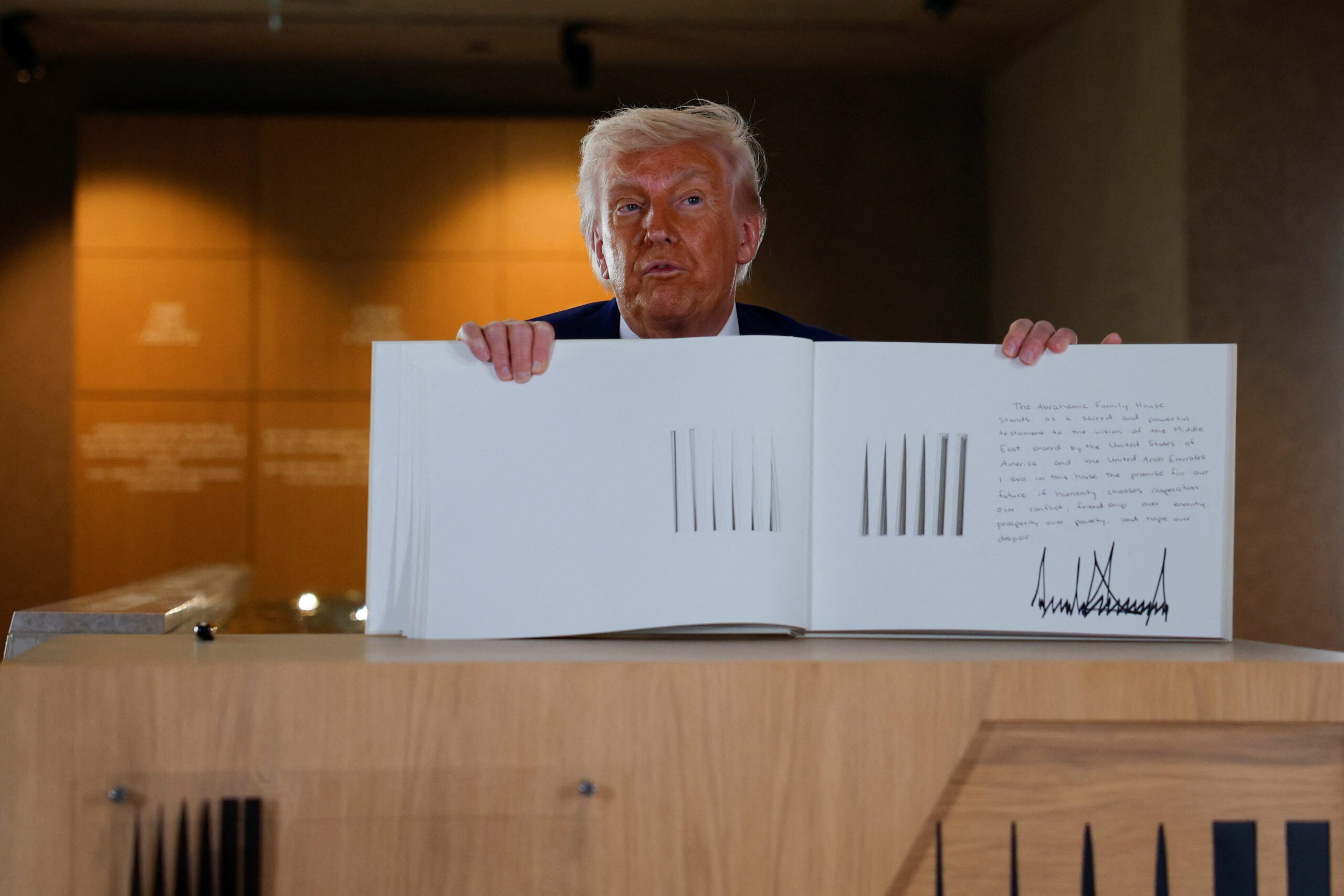 US President Donald Trump holds a guestbook as he visits the Abrahamic Family House in Abu Dhabi during the final stop of his Gulf visit