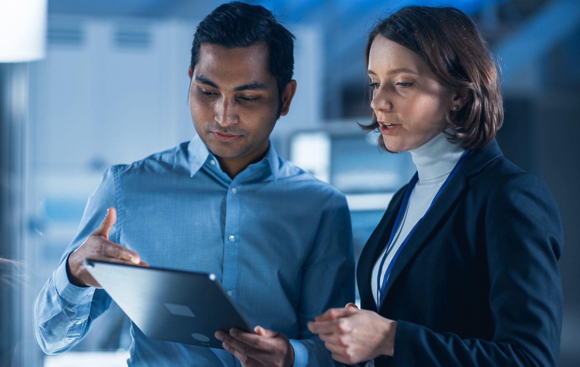2D0WH70 In Technology Research Facility: Female Project Manager Talks With Chief Engineer, they Consult Tablet Computer. Team of Industrial Engineers