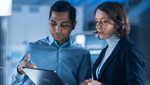 2D0WH70 In Technology Research Facility: Female Project Manager Talks With Chief Engineer, they Consult Tablet Computer. Team of Industrial Engineers