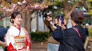 April 6, 2025, Tokyo, Japan: A woman wearing Japanese kimono poses for a pictures under the cherry blossoms in full bloom at Ueno Park in Tokyo. Cherry blossoms in full bloom at Tokyo's Ueno Park attract large crowds on a sunny Saturday. Around 800 trees, including the peak-blooming Somei Yoshino variety, create a stunning spring spectacle. (Credit Image: © Rodrigo Reyes Marin/ZUMA Press Wire)