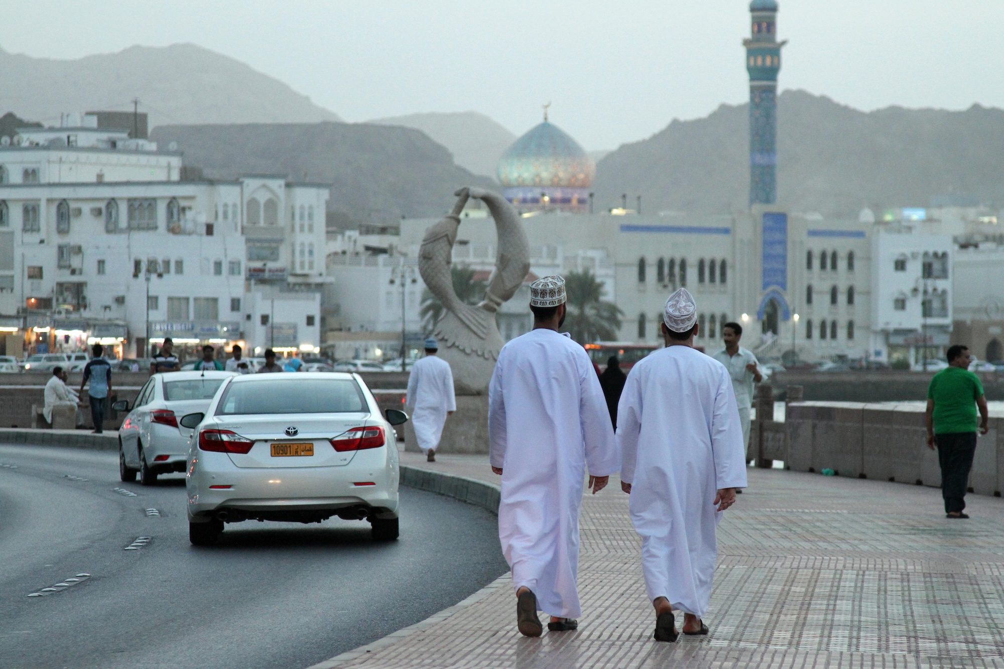 HTX2YD A pair of local Omani men walk along Muttrah corniche in the evening, in Muscat, Oman