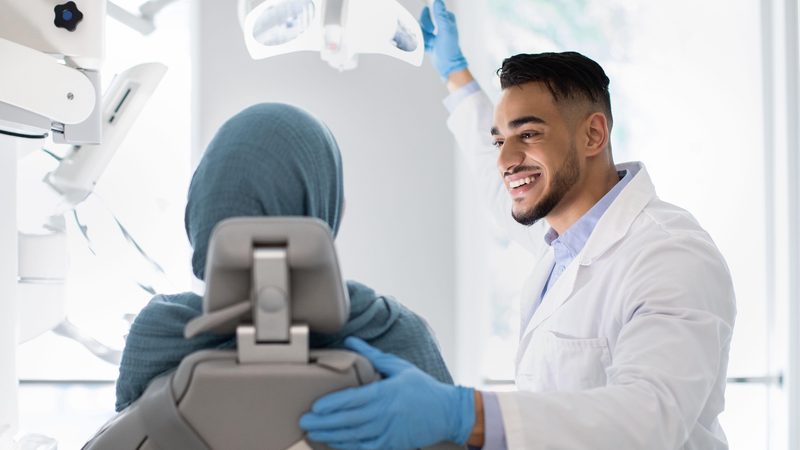 2GF2YC5 Young Arab Dentist Doctor Having Check Up With Islamic Female Patient