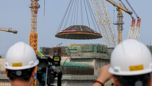 CHANGJIANG, CHINA - FEBRUARY 06: Reporters take photos of a 550-ton outer dome being hoisted in place at the construction site of the World's first commercial small modular reactor Linglong One, marking the main structure of its reactor building completed, on February 6, 2024 in Changjiang Li Autonomous County, Hainan Province of China. The reactor is expected to generate 1 bln kWh of power annually for 526,000 households upon operation. (Photo by Luo Yunfei/China News Service/VCG )No Use China.