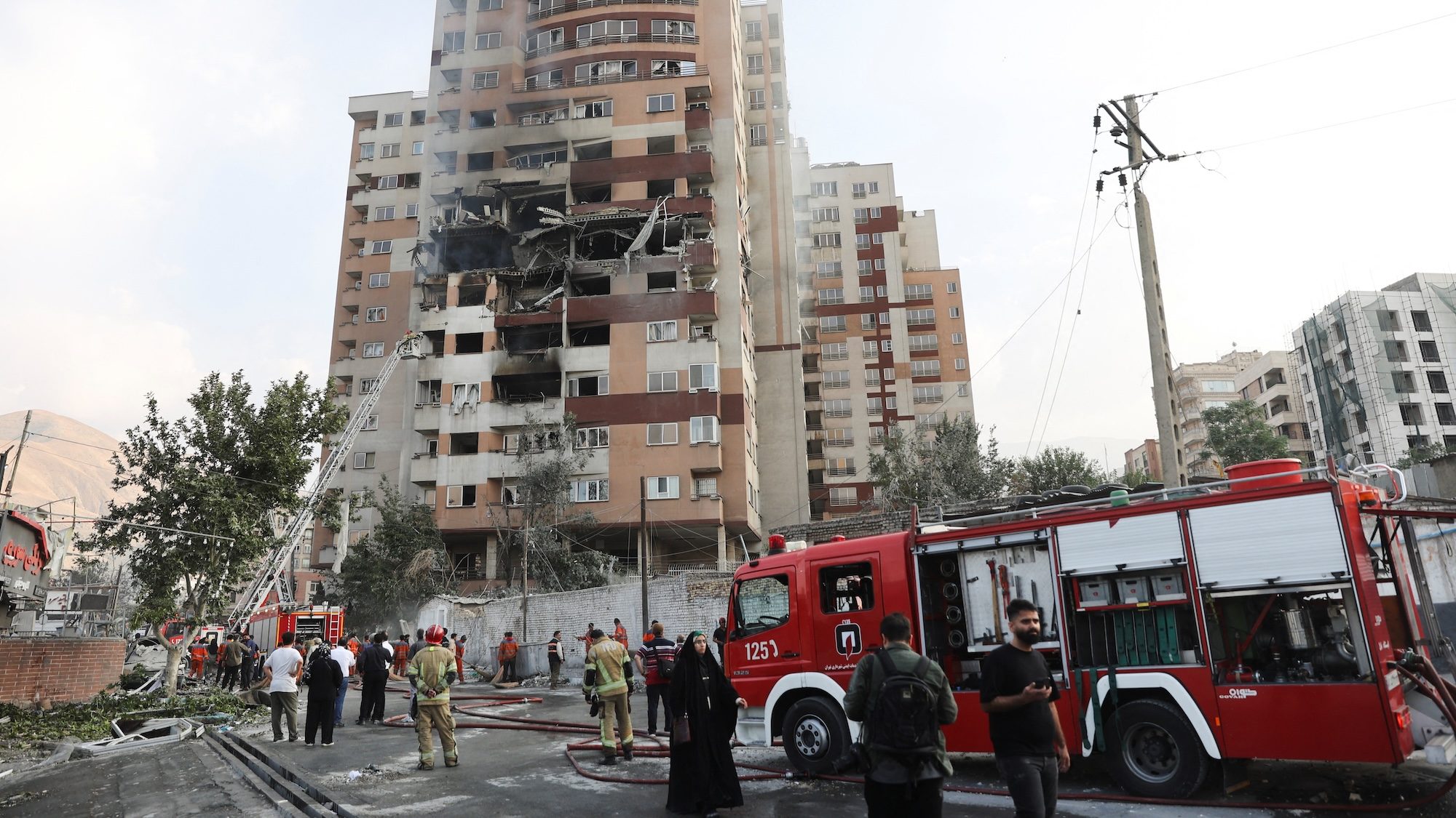 Firefighters at a damaged building in the aftermath of Israeli strikes, in Tehran, Iran