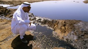 A worker checks a Kuwaiti oil lake